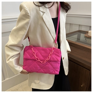 Detail of bright pink quilted crossbody bag featuring chain decor and rhombus patterns