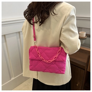 Détail d'un sac bandoulière matelassé rose vif avec une grosse chaîne assortie