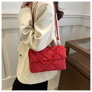 Detail of red quilted space cotton shoulder bag with plastic chain strap and flap closure