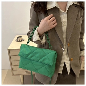 Modèle portant un sac bandoulière matelassé vert vif avec une grosse chaîne et rabat