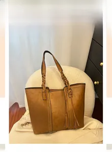 Detail of vintage brown leather tote with thick woven handle and tassel decoration