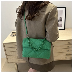 Quilted green shoulder bag with chain strap and crossbody style on a model