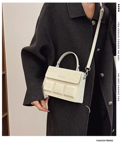 Detail of cream box bag showing embossed grid texture and silver metal hardware accents