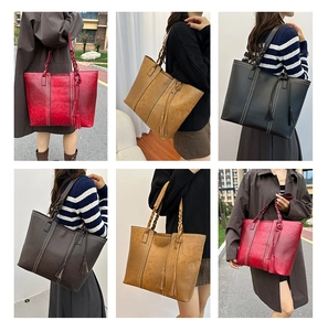 Detail view of large leather tote bag featuring woven strap and tassel charm accents