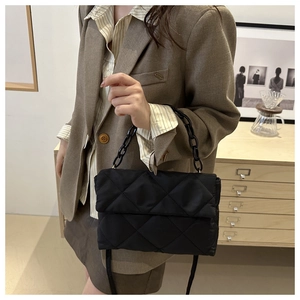 Detail of black quilted shoulder bag with chain strap styled on a brown blazer outfit