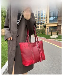 Close-up of red vintage faux leather tote with woven handles and tassel detail