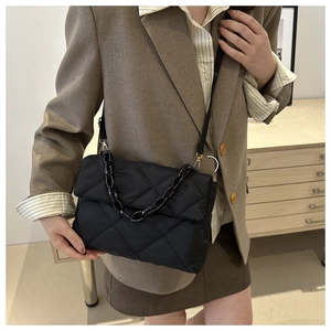 Détail d'un sac bandoulière en nylon matelassé noir avec chaîne en acrylique chic