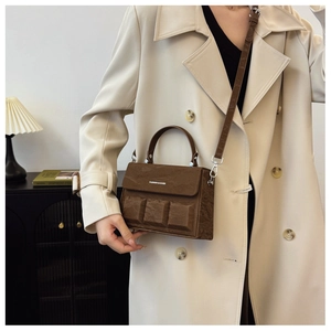 Detail of dark brown leather box bag with textured pockets and top handle on a model