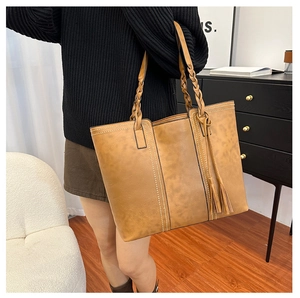 Detail of vintage brown tote bag with woven handle and side tassel decorations