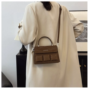 Detail of dark brown leather box bag featuring unique chocolate-block embossed texture