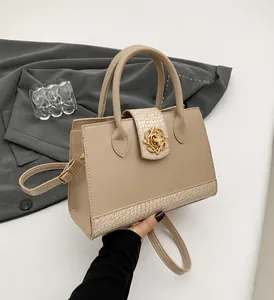 Detalle de bolso beige con textura de cocodrilo y cierre metálico floral dorado