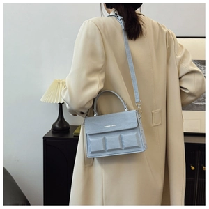 Detailed view of light blue box bag with square embossed pattern on a textured leather