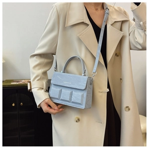 Detail of light blue textured leather box bag featuring unique 3D geometric square patterns