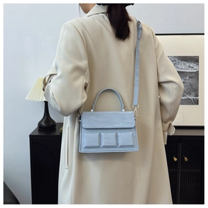 Detail of light blue crossbody bag with embossed squares and minimalist faux leather texture