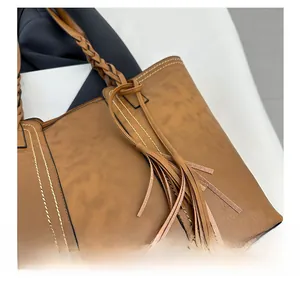Detail of vintage brown tote bag with woven handle, fringe charm and contrast stitching