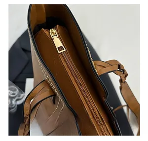 Detail of smooth gold zipper on premium brown lychee pattern leather tote bag