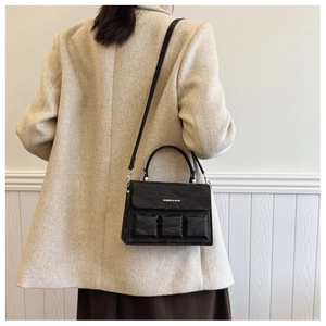 Detail of black textured crossbody bag featuring 3D padded accents and logo branding