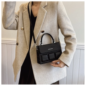 Detail of black textured crossbody box bag with geometric cubes and silver metal hardware