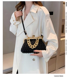Detail of black pleated shell bag with gold chunky chain handle and snap closure