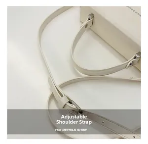 Detail of adjustable shoulder strap and silver hardware on cream leather box bag