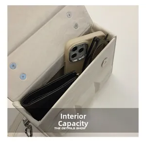 Internal capacity detail of minimalist cream box bag with phone and sunglasses