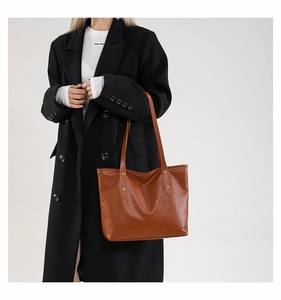 Detail of brown crocodile pattern leather tote with gold rivets and shoulder strap
