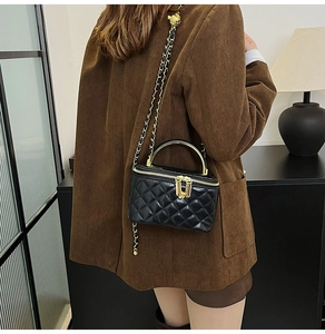 Sac à bandoulière matelassé noir avec chaîne dorée et poignée porté par un mannequin