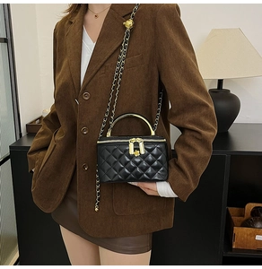 Détail du sac matelassé noir avec poignée en métal doré et fermeture éclair florale