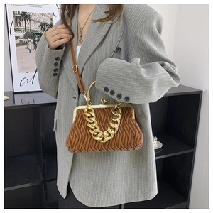 Macro detail of the brown pleated leather texture and gold chain on the crossbody bag