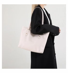 Detail view of large cream tote bag featuring lychee grain leather and gold rivets