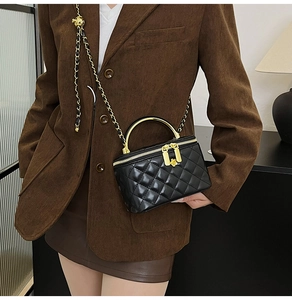Détail du mini sac vanité noir matelassé avec poignée dorée et tirettes de zip en fleur
