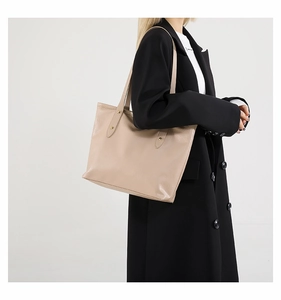 Detail view of large beige leather tote bag with metallic rivet strap reinforcements