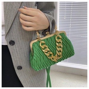 Detail of green pleated shell bag featuring gold chain strap and metal clip closure
