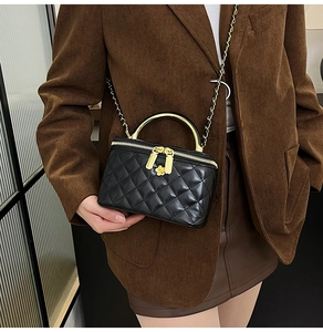 Détail du sac matelassé noir avec poignées dorées et fermeture fleurie sur le mannequin