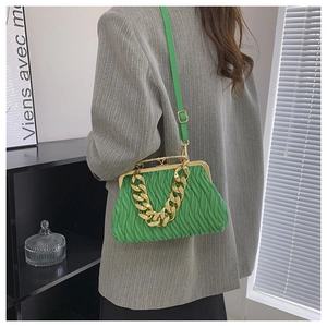 Detail of green ruched shell bag featuring gold chain handle on a grey blazer suit