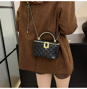 Détail d'un sac bandoulière noir matelassé avec poignée dorée sur veste velours