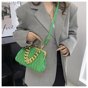 Detail of green pleated shell bag with chunky gold chain strap and metal clasp closure