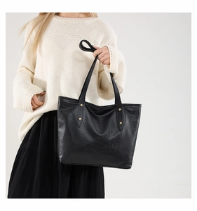 Close-up of black crocodile pattern leather tote bag with gold rivet details