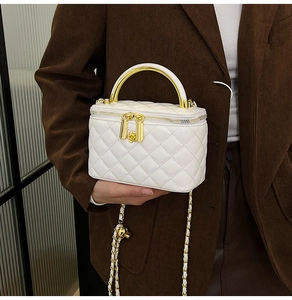 Détail du sac vanité en cuir matelassé blanc avec poignée dorée et zip fleuri