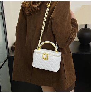 Sac à bandoulière matelassé blanc avec chaîne dorée et poignée porté par un mannequin