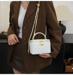 Vue détaillée d'un sac à bandoulière matelassé blanc avec poignée en or et chaîne dorée