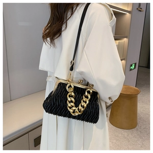 Detail of black pleated crossbody bag with gold chain and vintage metal clasp