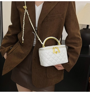 Gros plan d'un sac à main blanc matelassé avec chaîne dorée et poignée en métal