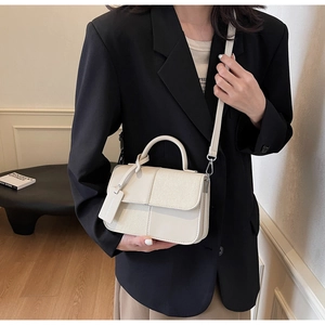 Détail d'un sac à main blanc crème en cuir avec empiècements texturés et poignée élégante