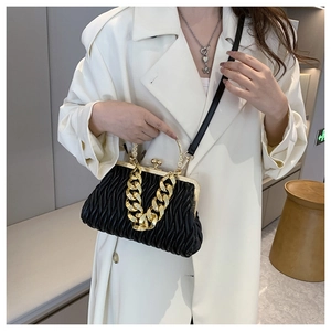 Detailed view of black pleated crossbody bag with chunky gold chain and leather strap