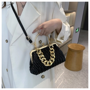 Close-up of black matelassé shell bag with vintage gold metal clasp and chain strap
