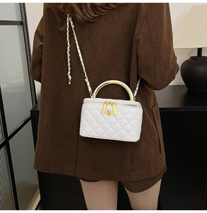 Gros plan d'un mini sac matelassé blanc avec fleur dorée et bandoulière chaîne