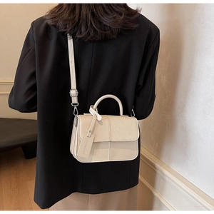 Détail du sac bandoulière beige contrasté avec texture tissée et bandoulière amovible