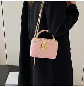 Détail du sac en cuir matelassé rose avec poignée en métal doré et bandoulière à chaîne