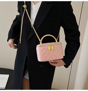 Détail du sac bandoulière rose matelassé avec poignée dorée et chaîne sur un mannequin